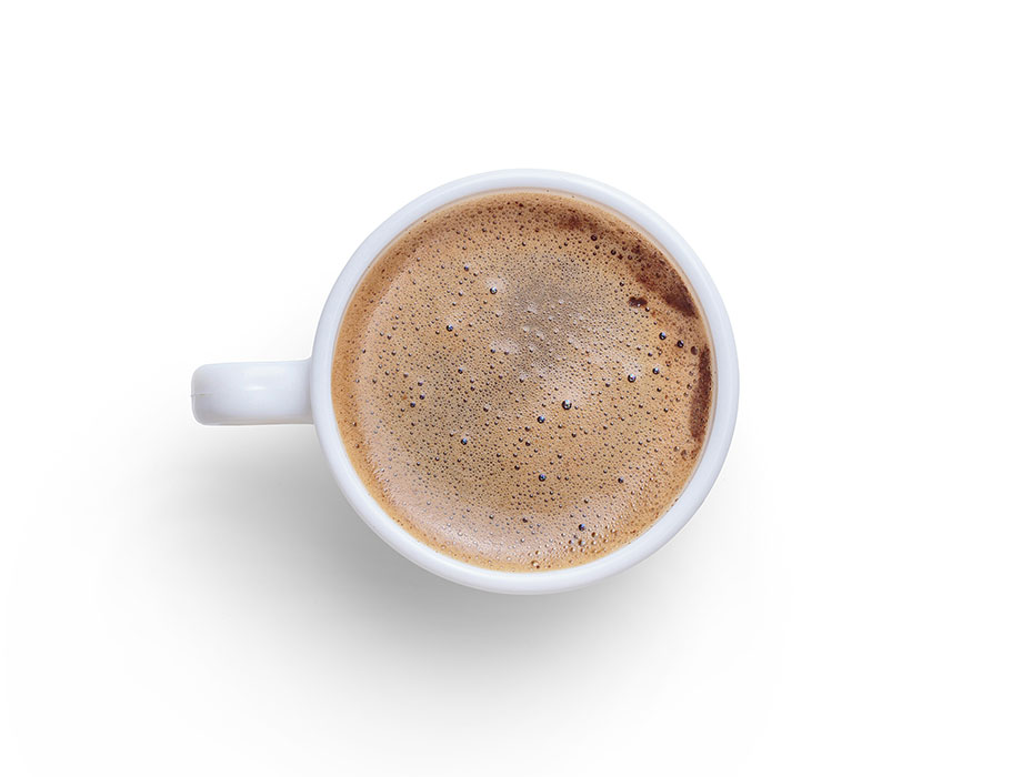 Frothy coffee in a white mug against a white background